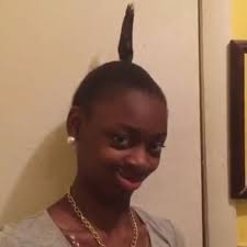 Uma jovem sorri para a câmera exibindo um penteado único com uma mecha de cabelo apontando para cima.